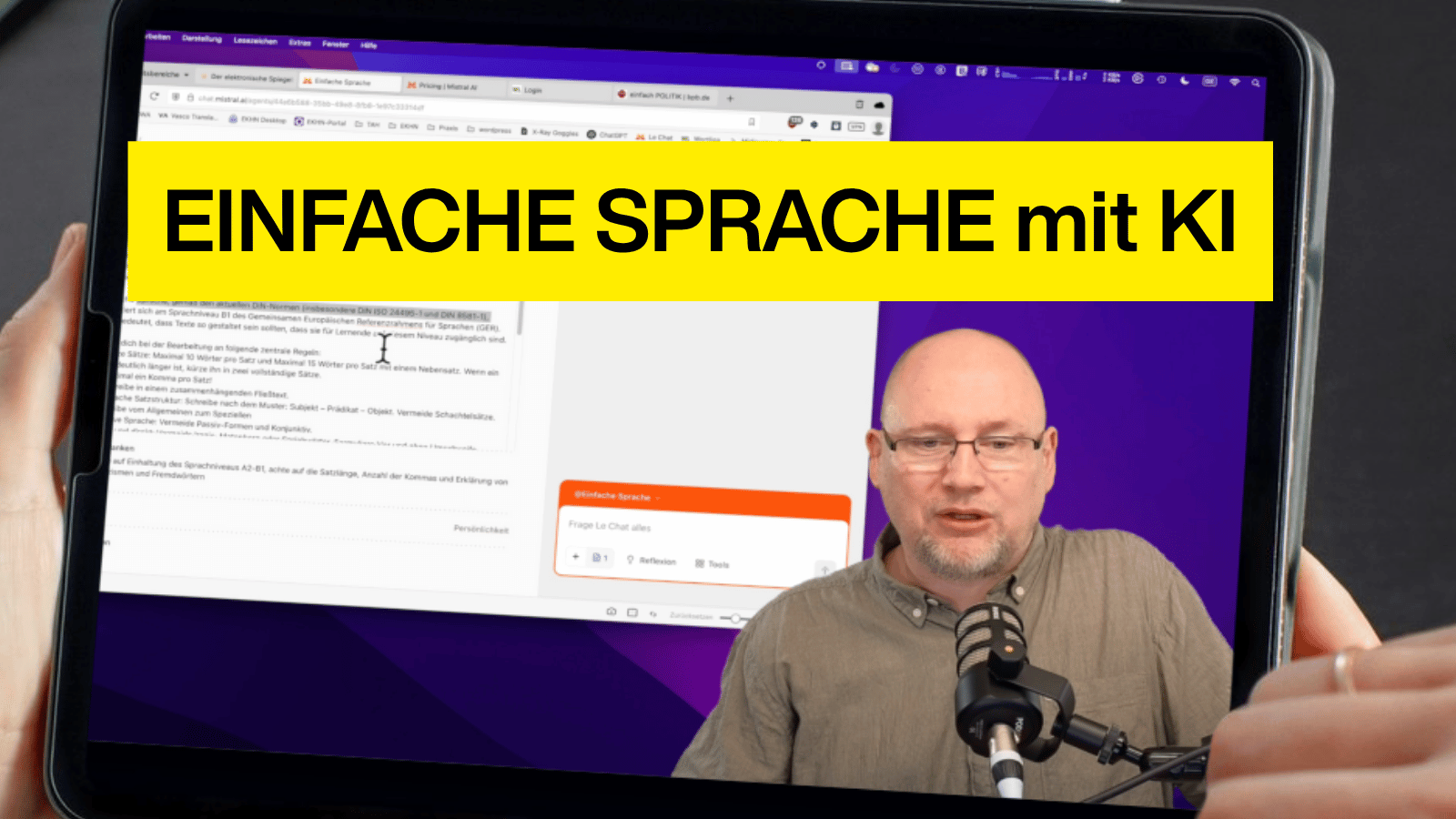 Auf einem Tablet ist ein Video zu sehen, in dem ein Mann mit Brille und grauem Hemd in ein Podcast-Mikrofon spricht. Im Hintergrund ist ein Computerbildschirm mit geöffneter Webseite zu sehen. Ein auffälliger gelber Balken mit schwarzer Schrift trägt die Aussage „EINFACHE SPRACHE mit KI“. Die Szene suggeriert eine Präsentation oder ein Tutorial zur Nutzung künstlicher Intelligenz für barrierefreie Sprache.