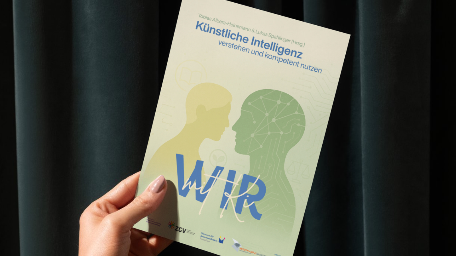 Eine Hand, die das Buch hier mit KI in die Kamera hält.